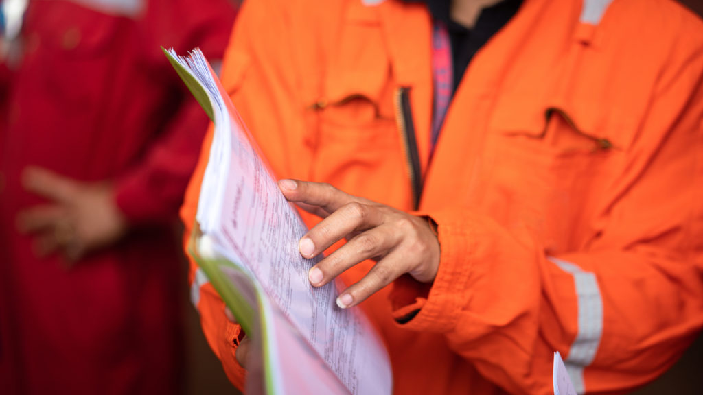 action of a supervisor pointing on document paper for discussion during a safety audit and operation commisionning. indsutrial worker people photo. selective focus at the people hand.