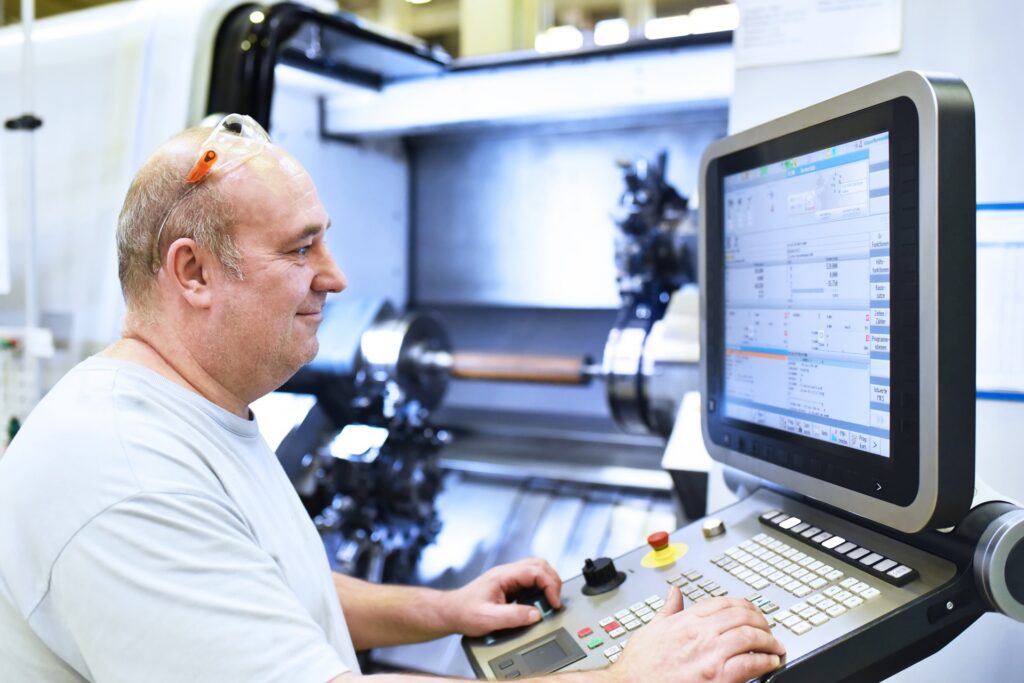 facharbeiter in der industrie bedient eine cnc drehmaschine zur mechanischen bearbeitung im maschinenbau // skilled workers in the industry uses a cnc lathe for machining in mechanical engineering